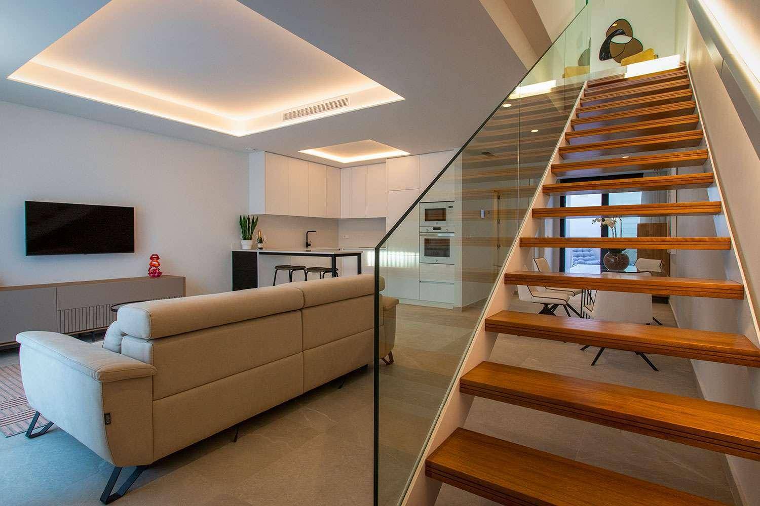 Offener Wohnbereich mit moderner Treppe, integrierter Küche und stilvoller Einrichtung, sehr einladend.