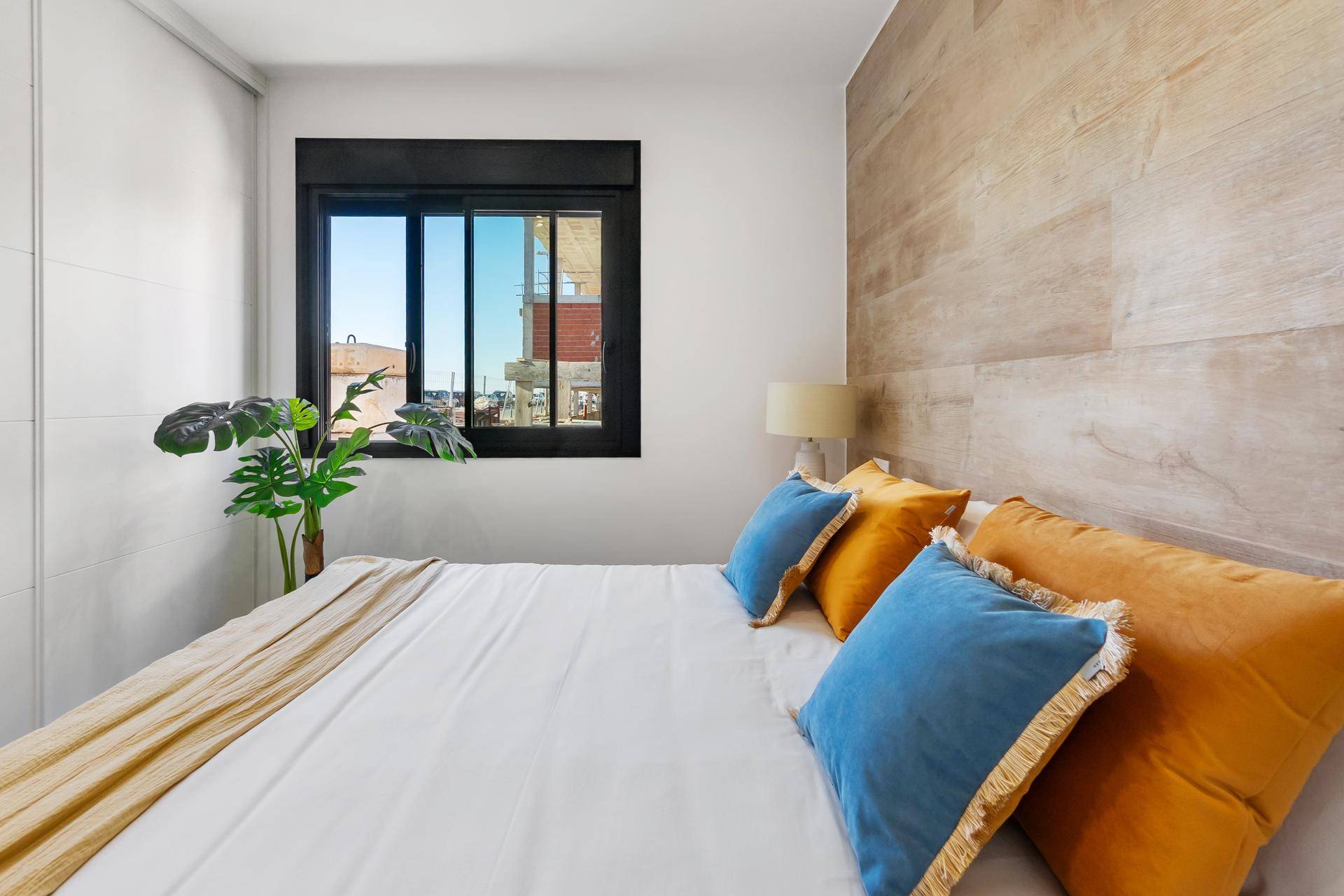Gemütliches Schlafzimmer mit Doppelbett, Holzwand und Blick nach draußen.