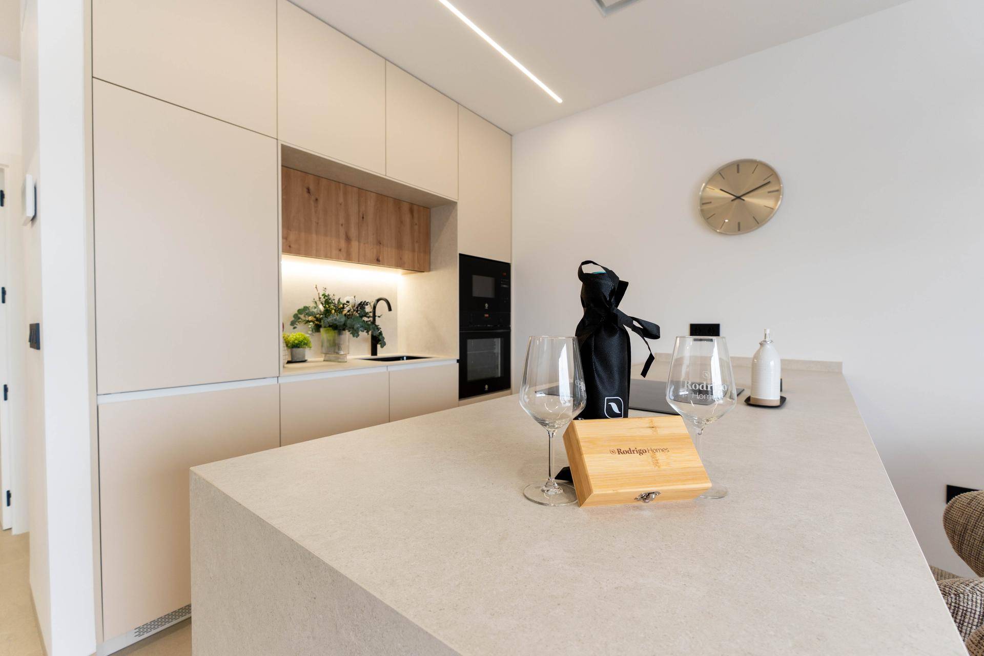 Moderne Küche mit beigen Schränken, integrierten Geräten und einer Arbeitsplatte aus Stein.