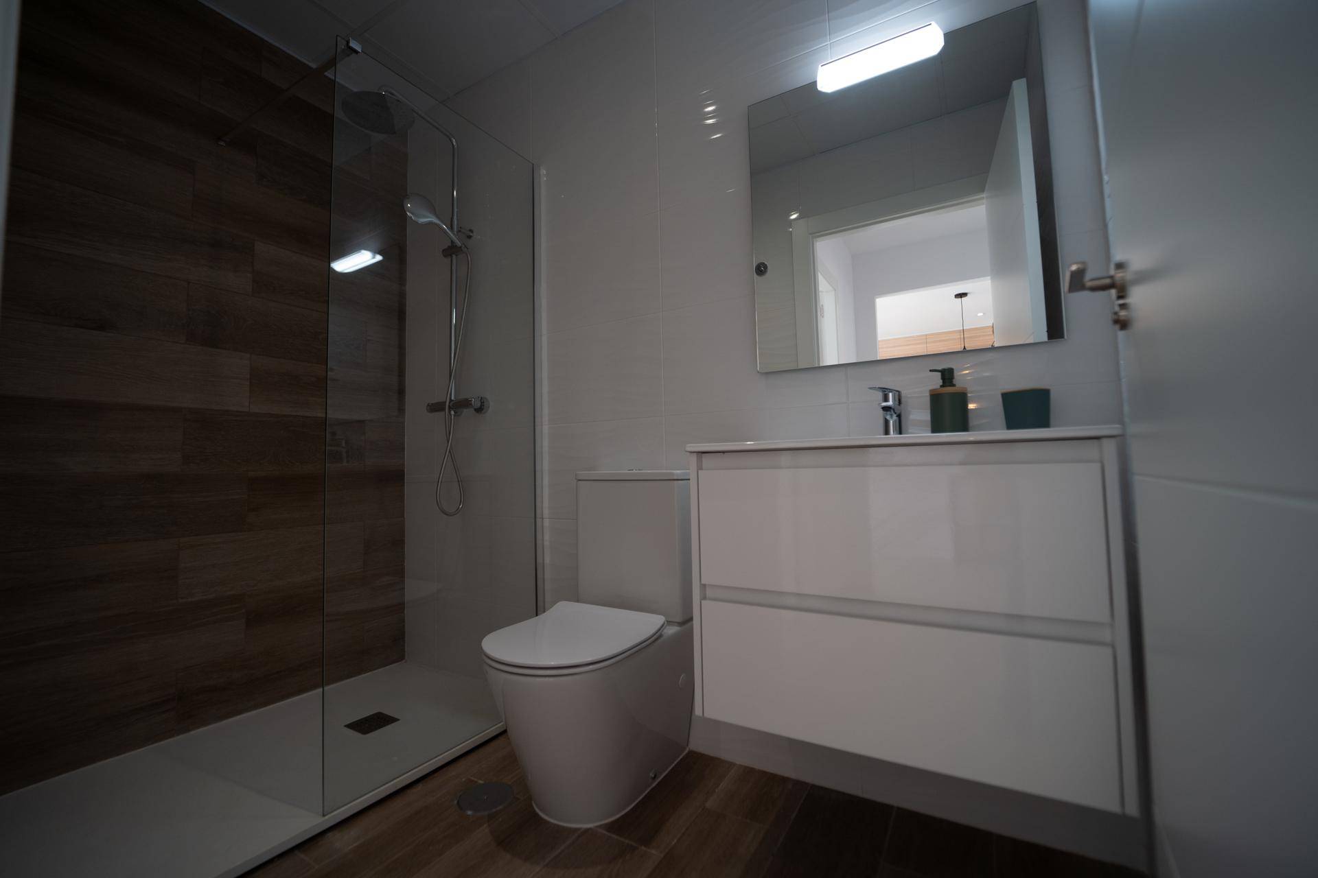 Modernes Badezimmer mit Dusche, Toilette und Einzelwaschbecken mit Spiegelschrank.