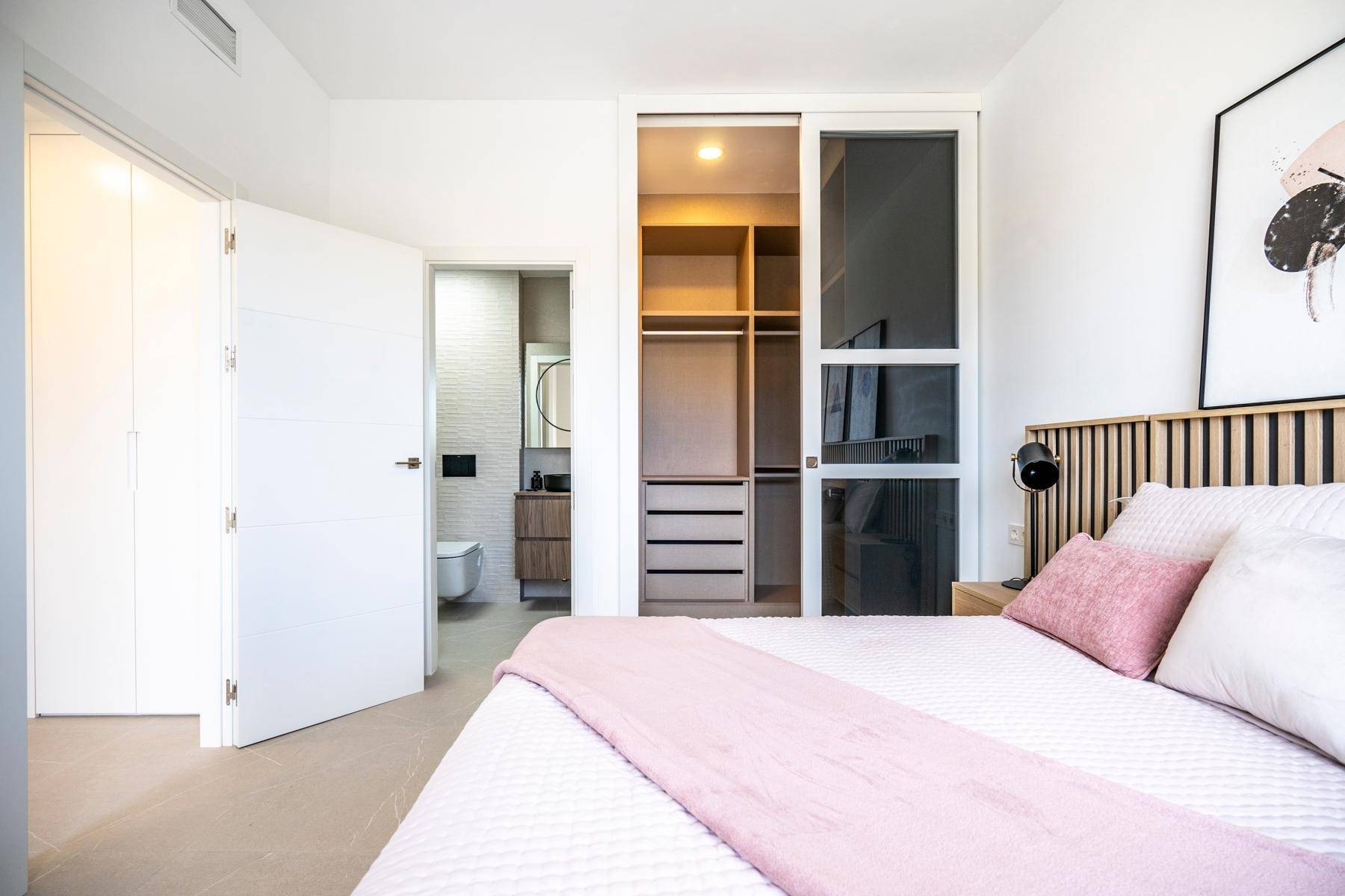 Helles Schlafzimmer mit Zugang zu einem begehbaren Kleiderschrank und einem modernen Badezimmer.