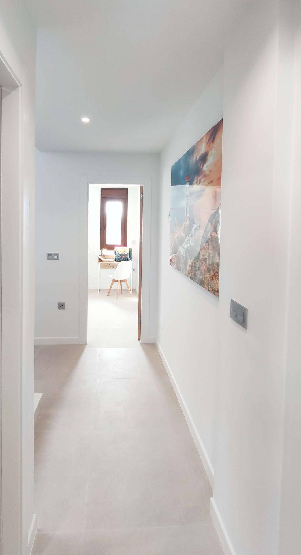 Heller Flur mit moderner Kunst an der Wand und Blick in einen weiteren Raum.