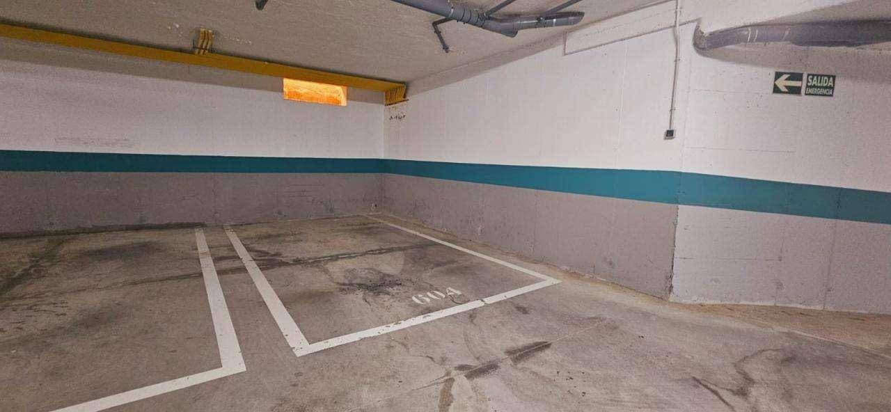 Tiefgarage mit markierten Parkplätzen und Notausgangsbeschilderung.