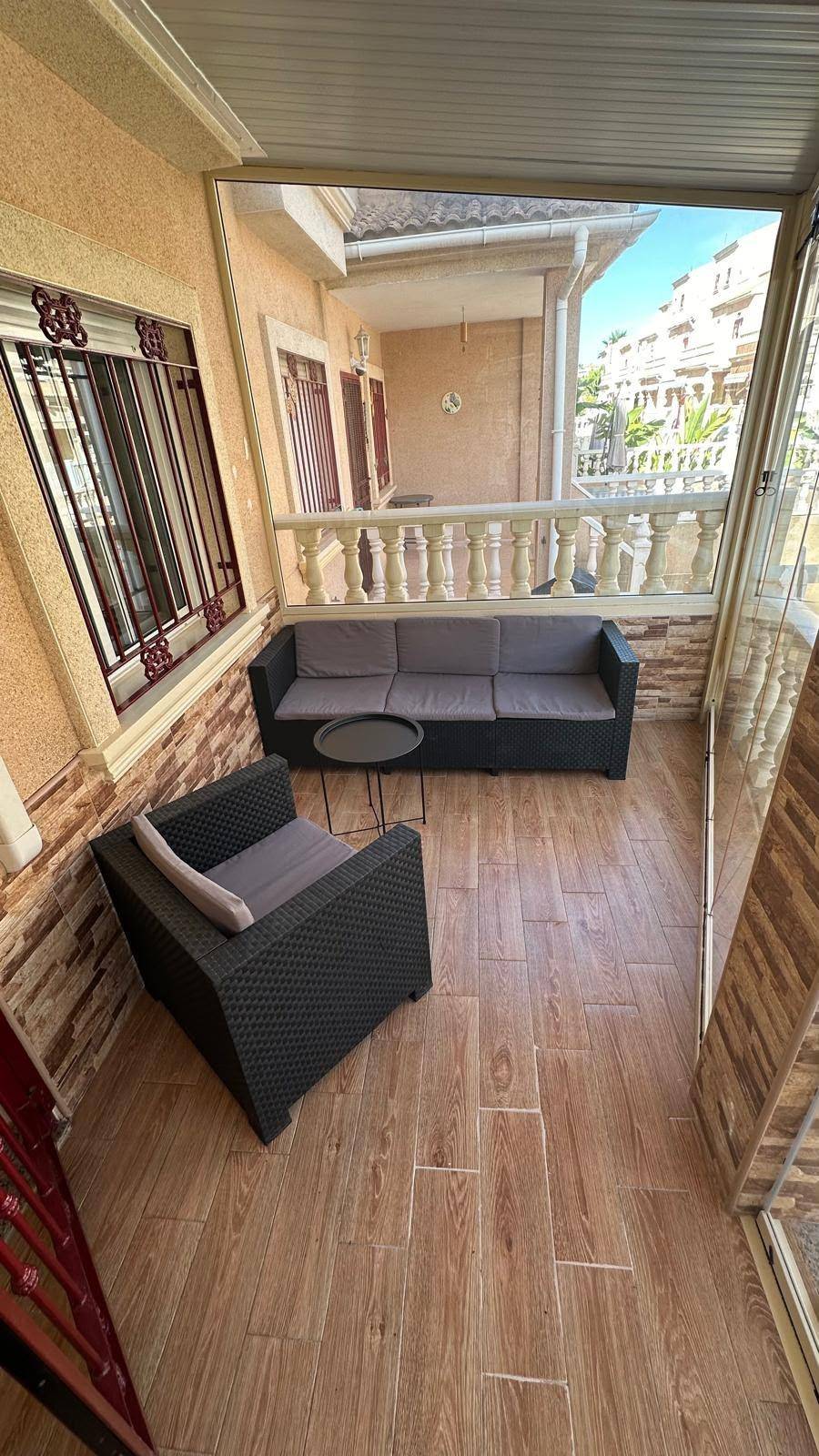 Verglaster Balkon mit Loungemöbeln und Blick auf die Umgebung.