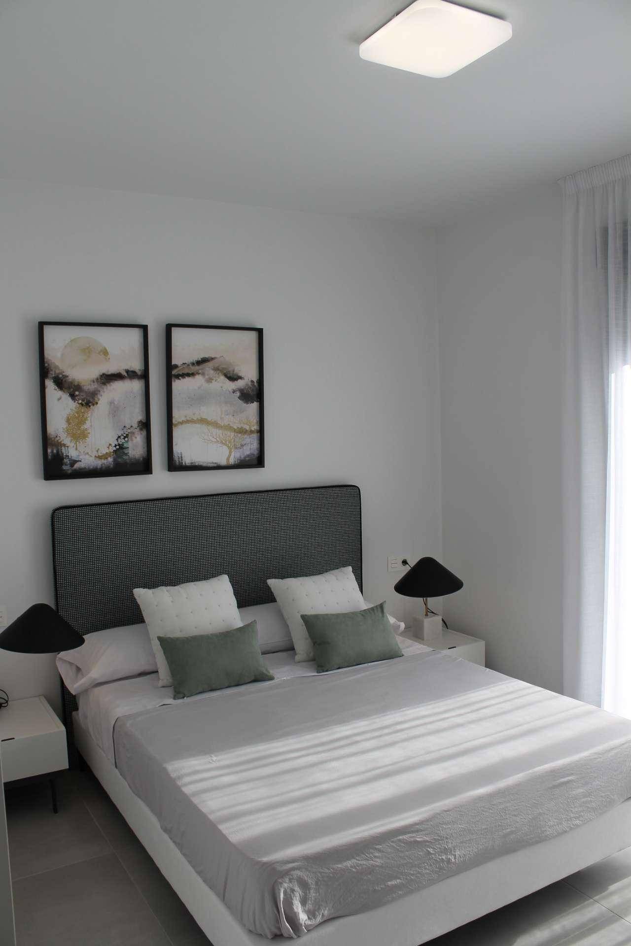 Helles Schlafzimmer mit Doppelbett, Nachttischen und moderner Wanddekoration.
