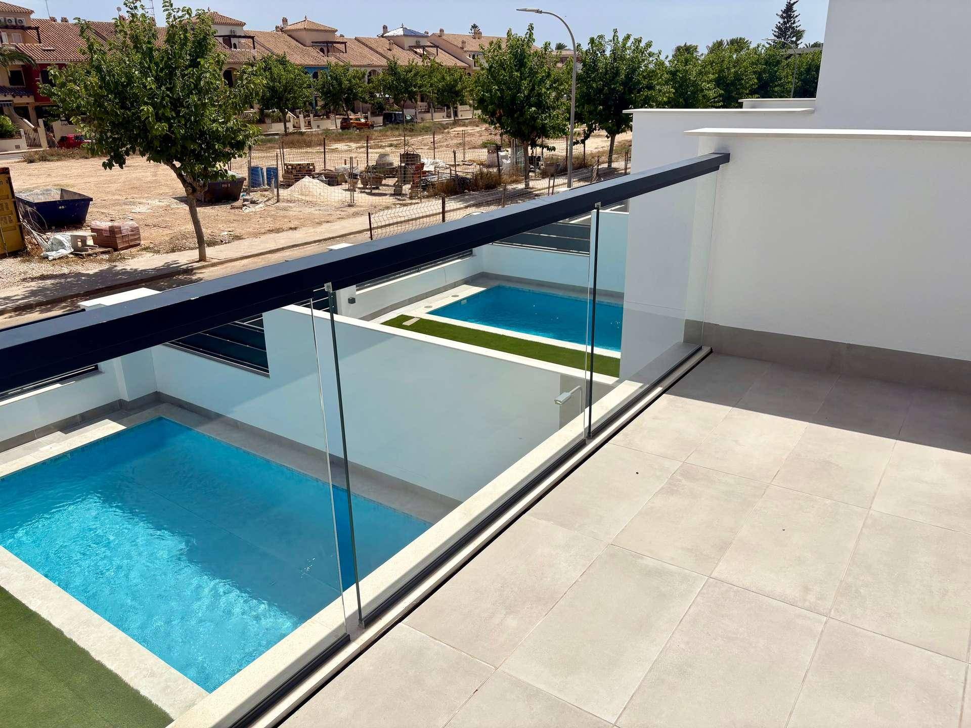 Blick von einer oberen Terrasse auf zwei private Pools und die umliegende Bebauung.