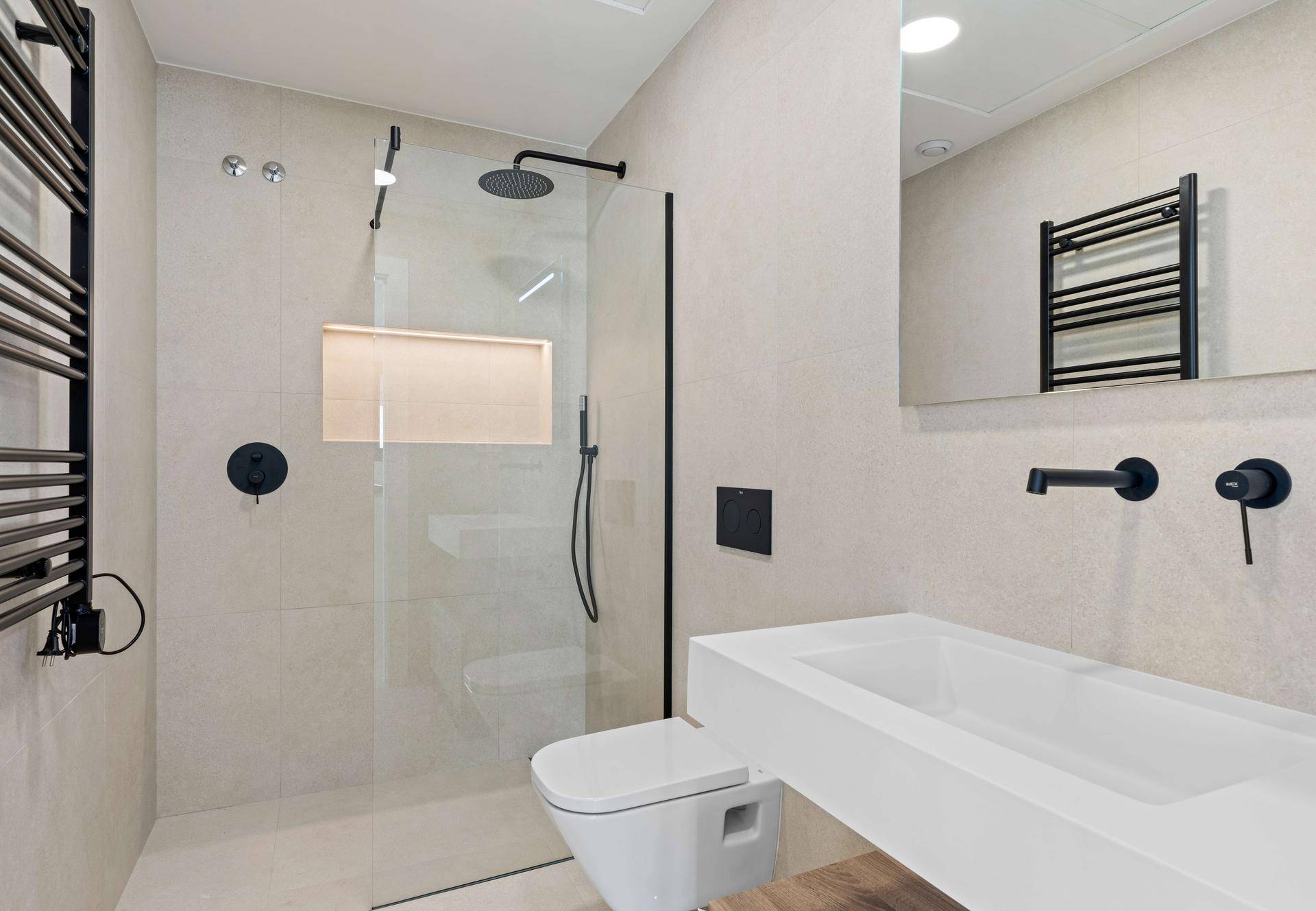 Modernes Badezimmer mit begehbarer Dusche, Wand-WC und beheiztem Handtuchhalter.