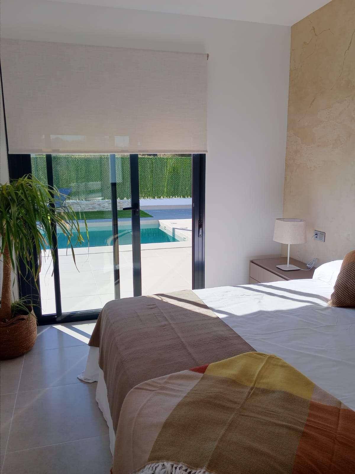 Helles Schlafzimmer mit großem Fenster und direktem Zugang zum Poolbereich.