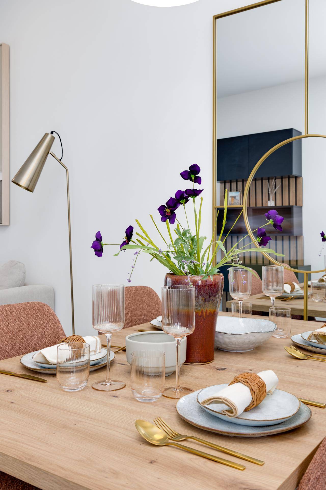 Detailaufnahme des elegant gedeckten Esstisches mit floraler Dekoration und Spiegelwand.
