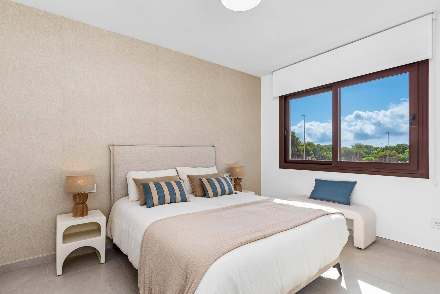 Geräumiges Hauptschlafzimmer mit Doppelbett, beiger Wand und großem Fenster mit weitem Blick.