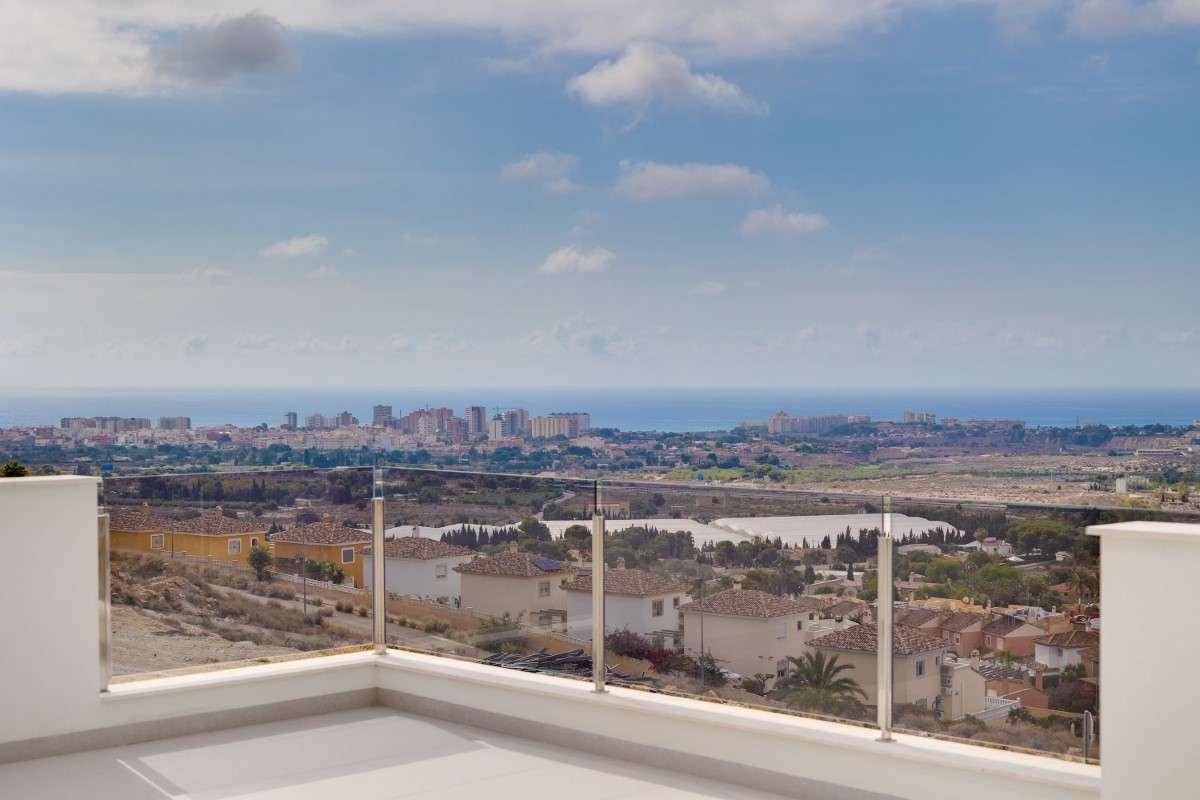 Helle Dachterrasse mit Glasgeländer und Panoramablick auf die Stadt und das Meer.