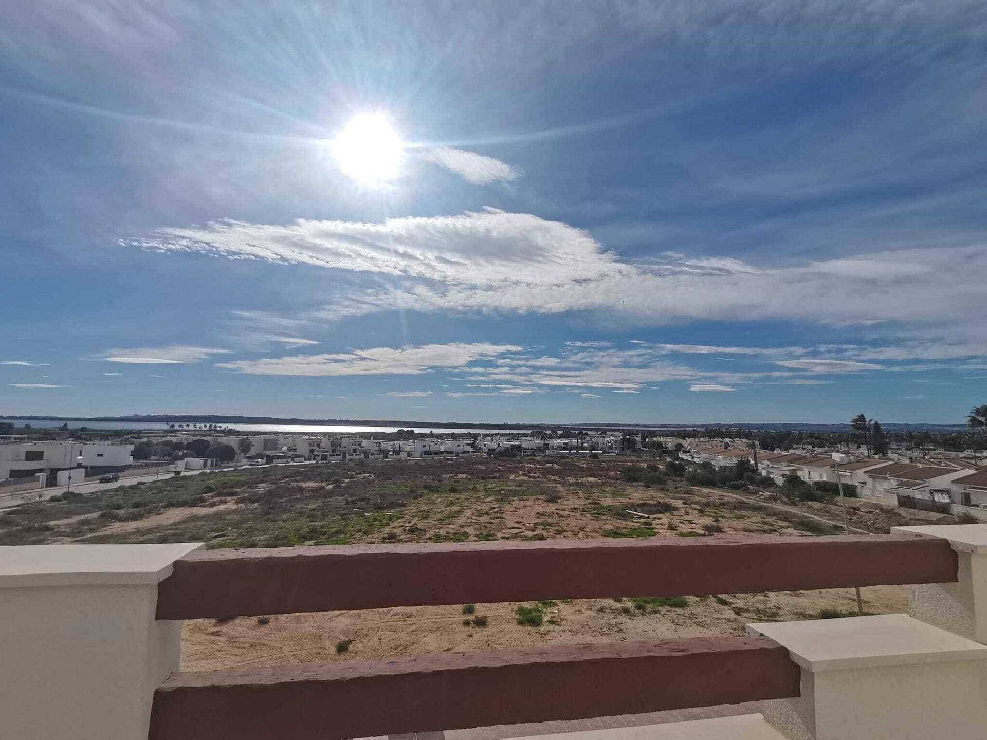 Weitläufiger Blick auf die Landschaft, das Meer und die umliegende Bebauung unter blauem Himmel.