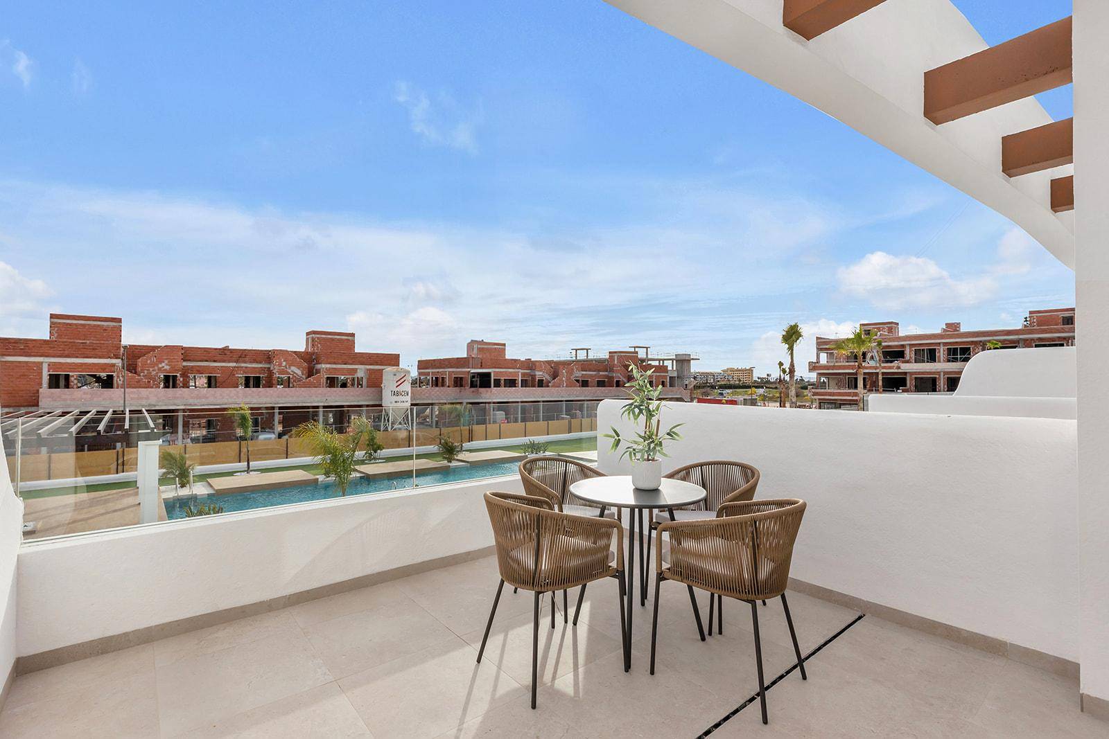 Balkon mit Sitzgelegenheiten und Blick auf den Gemeinschaftspool und die umliegenden Gebäude.