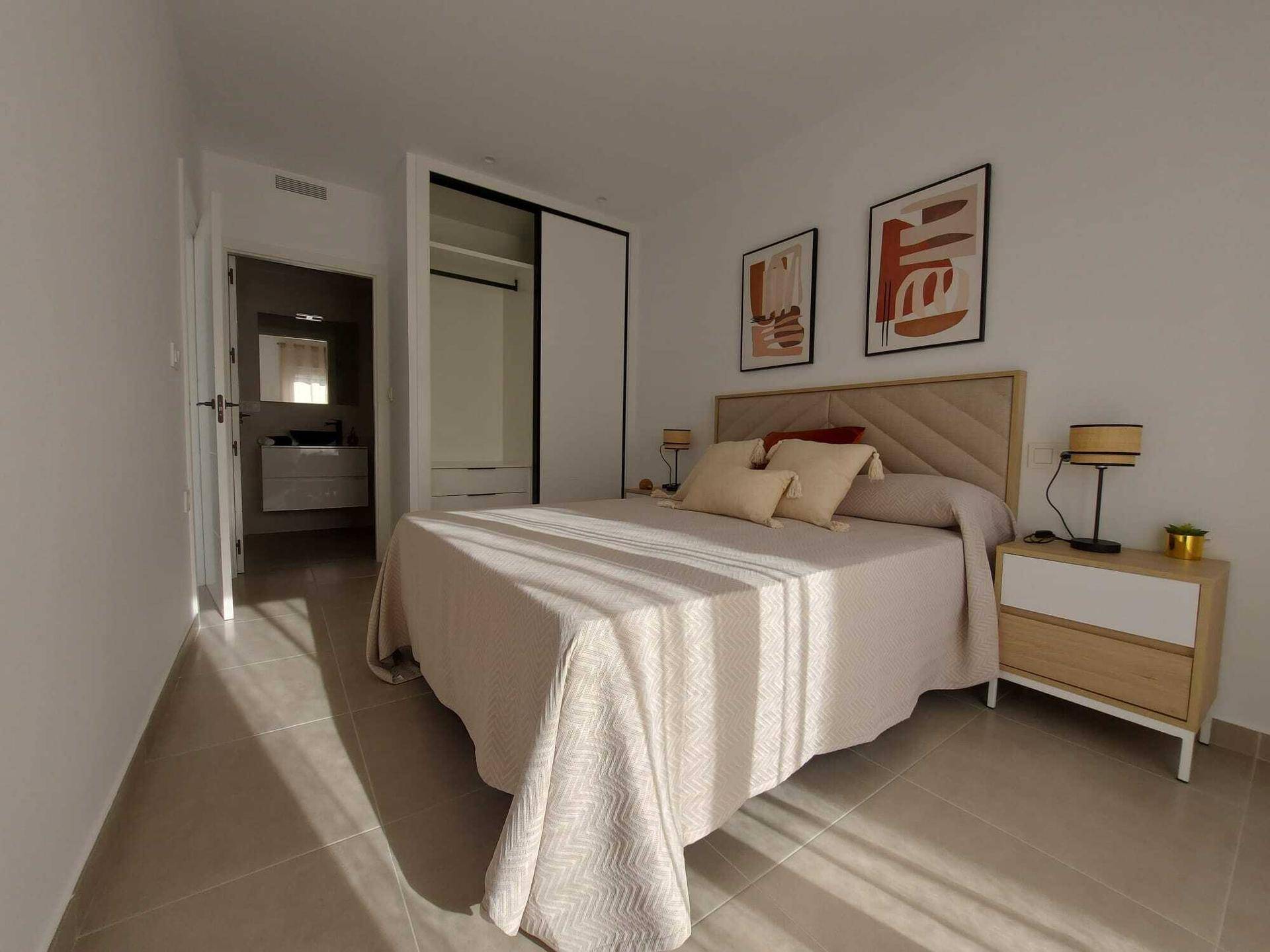 Helles Schlafzimmer mit Doppelbett, Einbauschrank und Zugang zu einem eigenen Bad.