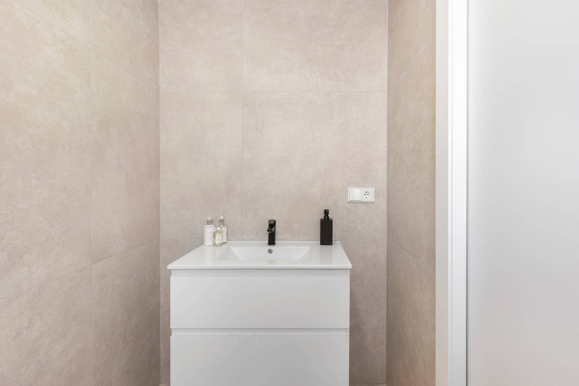 Modernes Badezimmer mit Einzelwaschbecken und hellen Fliesen.