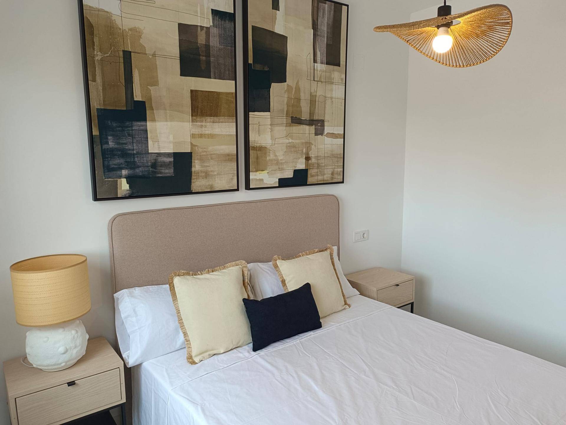 Gemütliches Schlafzimmer mit Doppelbett, Nachttischen und abstrakten Kunstwerken.