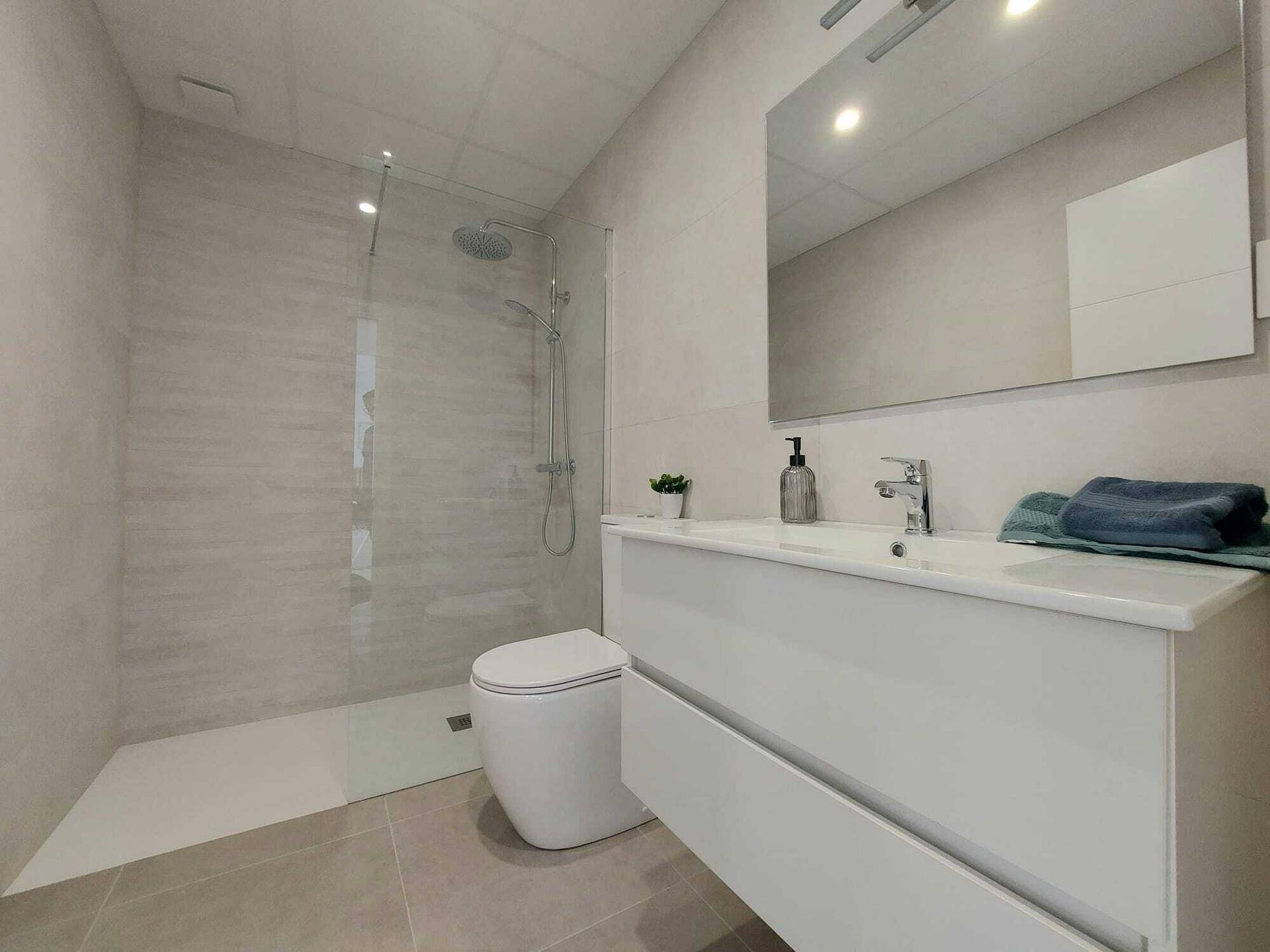 Modernes Badezimmer mit begehbarer Dusche, wandhängendem WC und großem Waschtisch.