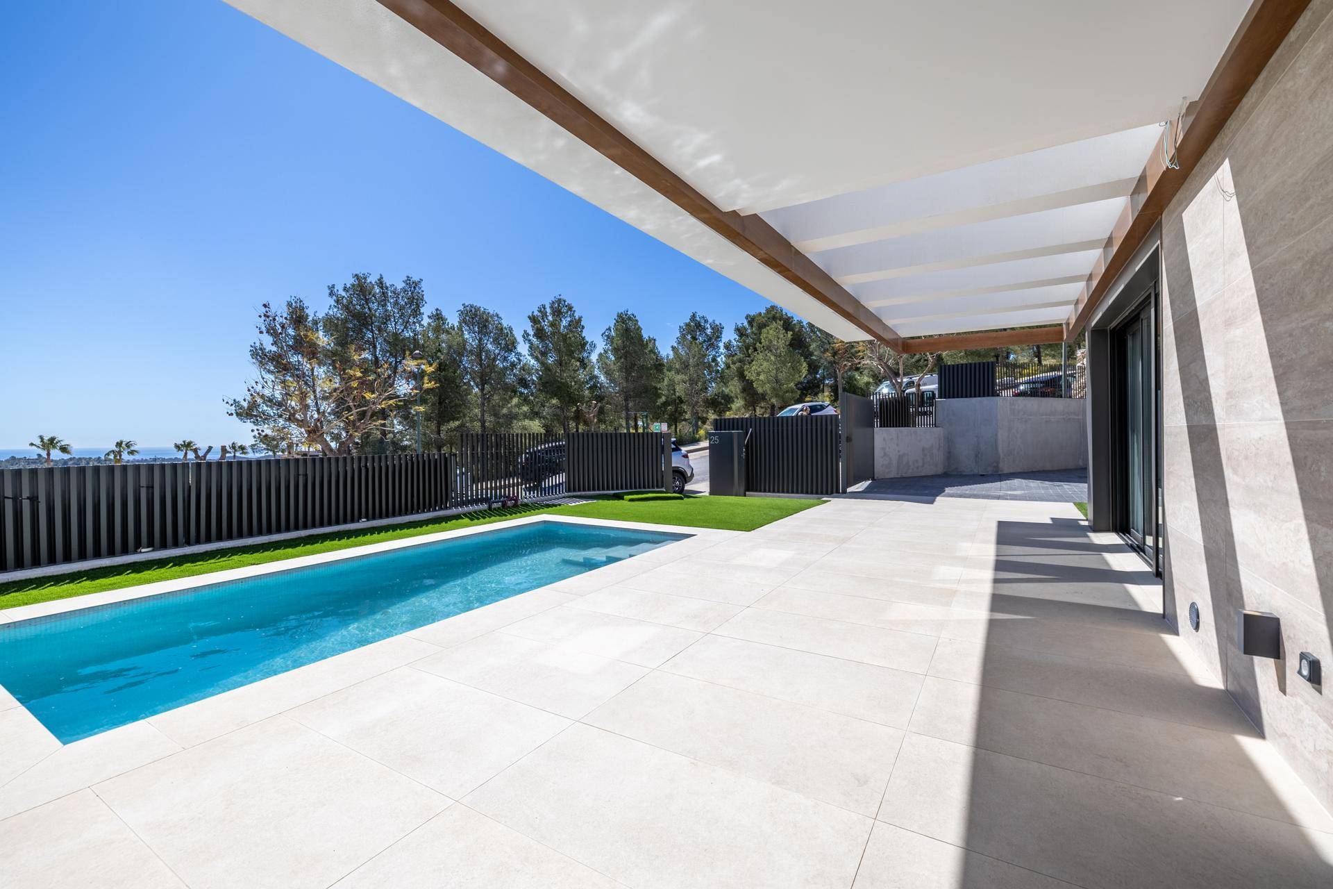 Großzügige Poolterrasse mit hellen Fliesen und weitem Blick auf die bewaldete Umgebung.