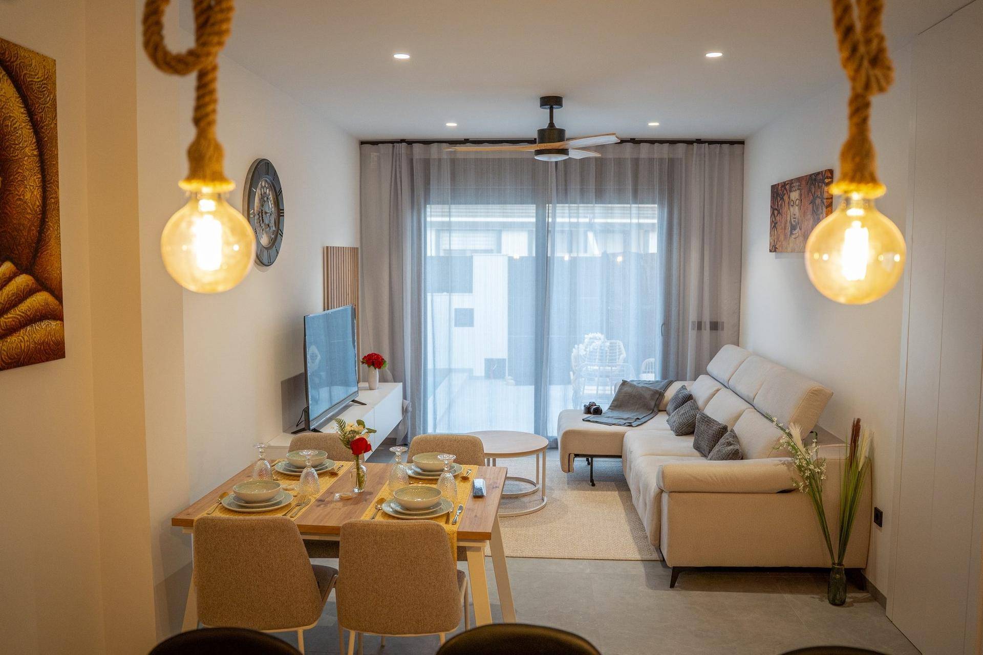 Heller Wohn-Essbereich mit modernem Sofa, Esstisch und Zugang zu einer Außenterrasse.
