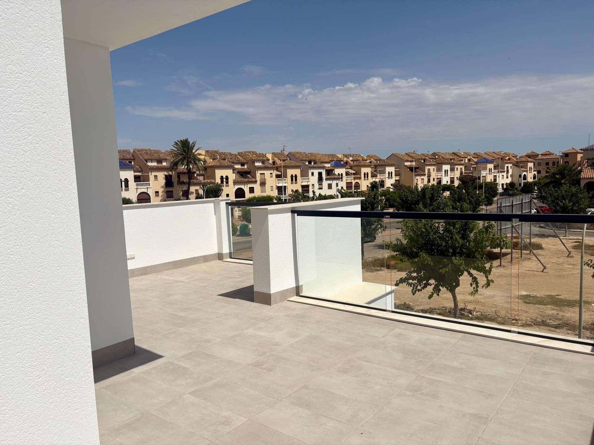 Geräumige Dachterrasse mit Fliesenboden und Glasgeländer, bietet weite Aussicht auf die Umgebung.