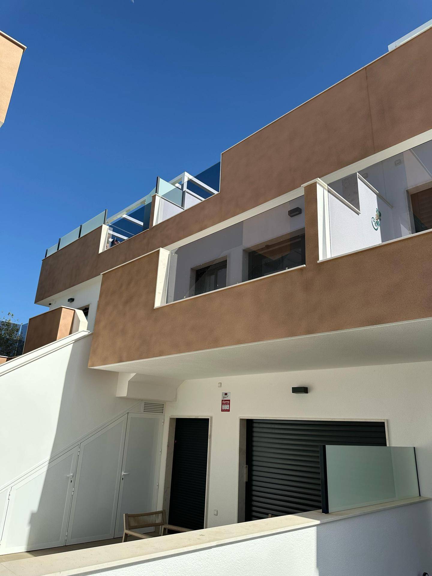 Moderne Fassade der Reihenhäuser mit Balkonen und Eingangsbereichen unter blauem Himmel.