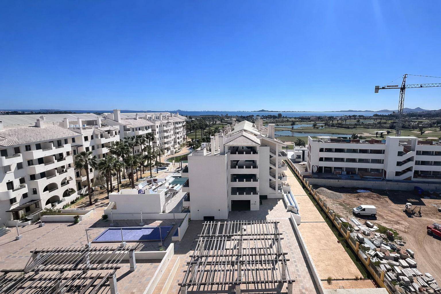 Weitläufige Apartmentanlage mit Blick auf das Meer und umliegende Golfplätze unter klarem Himmel.