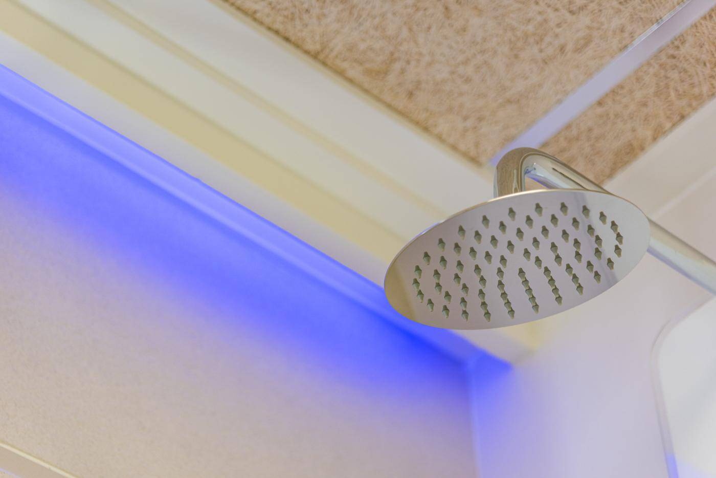 Moderne Regendusche mit blauer LED-Beleuchtung in einem stilvollen Badezimmer.