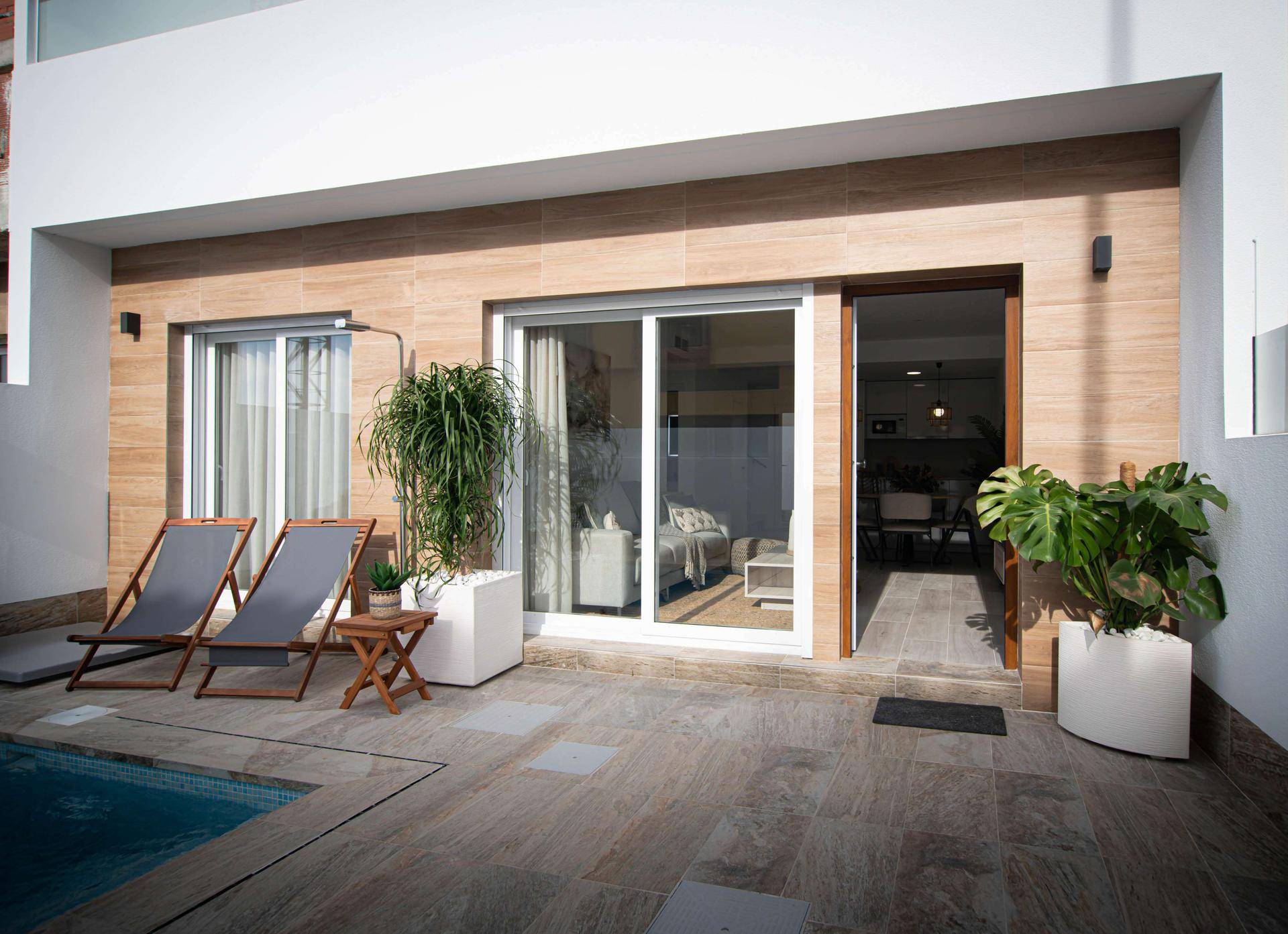Sonniger Patio mit kleinem Pool und offenem Zugang zum hellen Wohnbereich des Hauses.