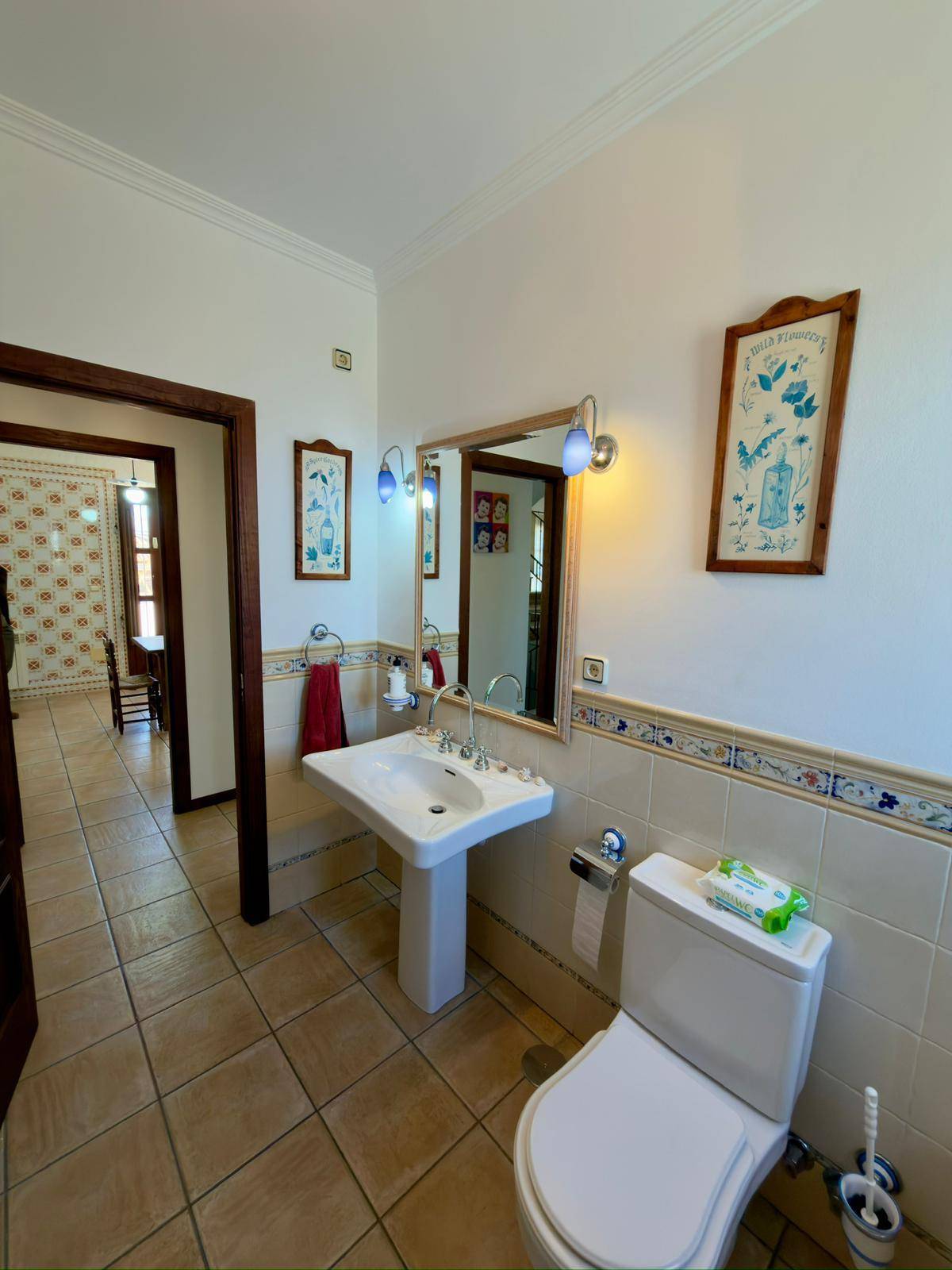 Traditionelles Badezimmer mit Standwaschbecken, WC und dekorativen Wandfliesen.