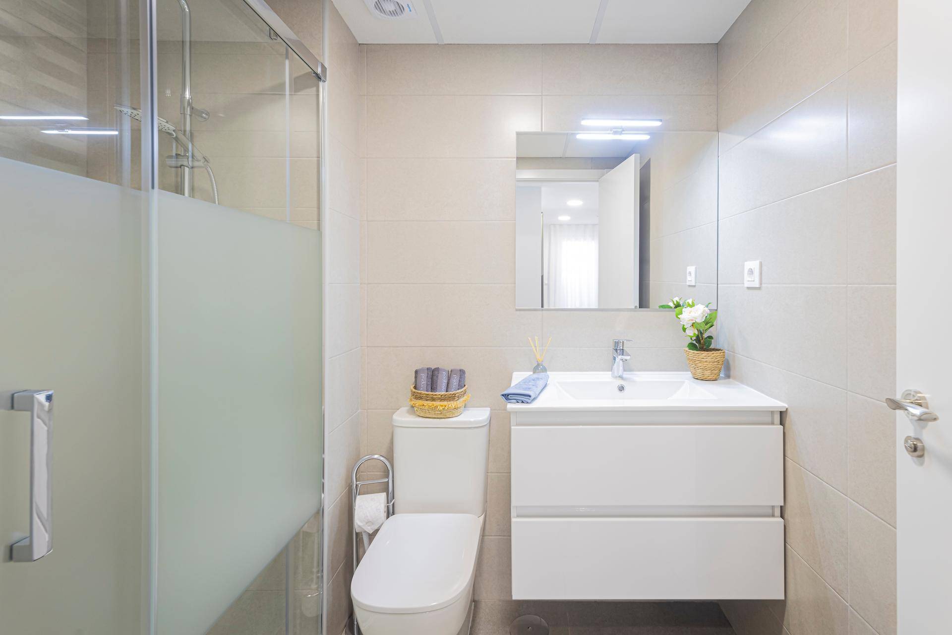 Modernes Badezimmer mit Duschkabine, Waschbecken und Wandspiegel.