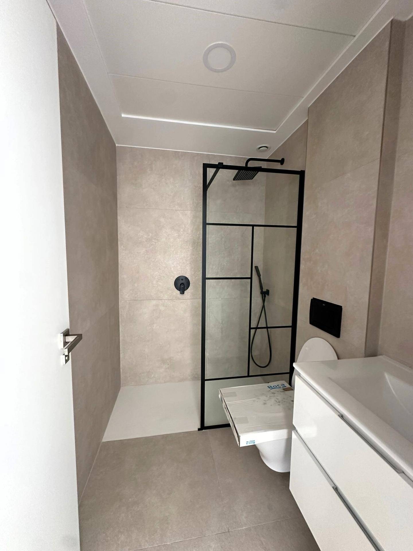 Modernes Badezimmer mit begehbarer Dusche, Wand-WC und hellen Fliesen.