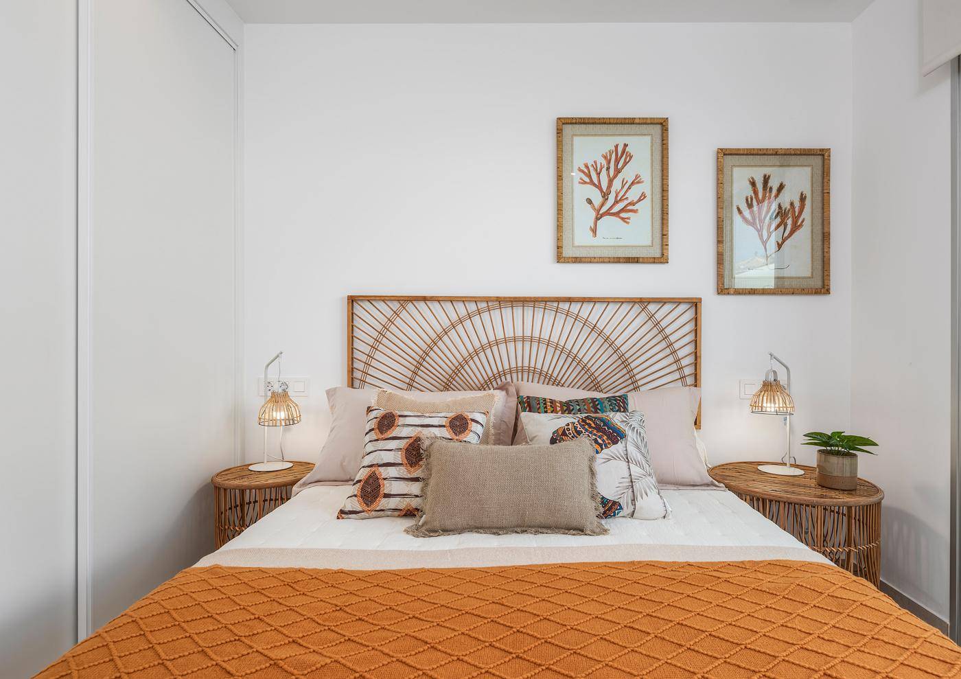 Gemütliches Schlafzimmer mit Rattan-Kopfteil, passenden Nachttischen und warmen Farben.