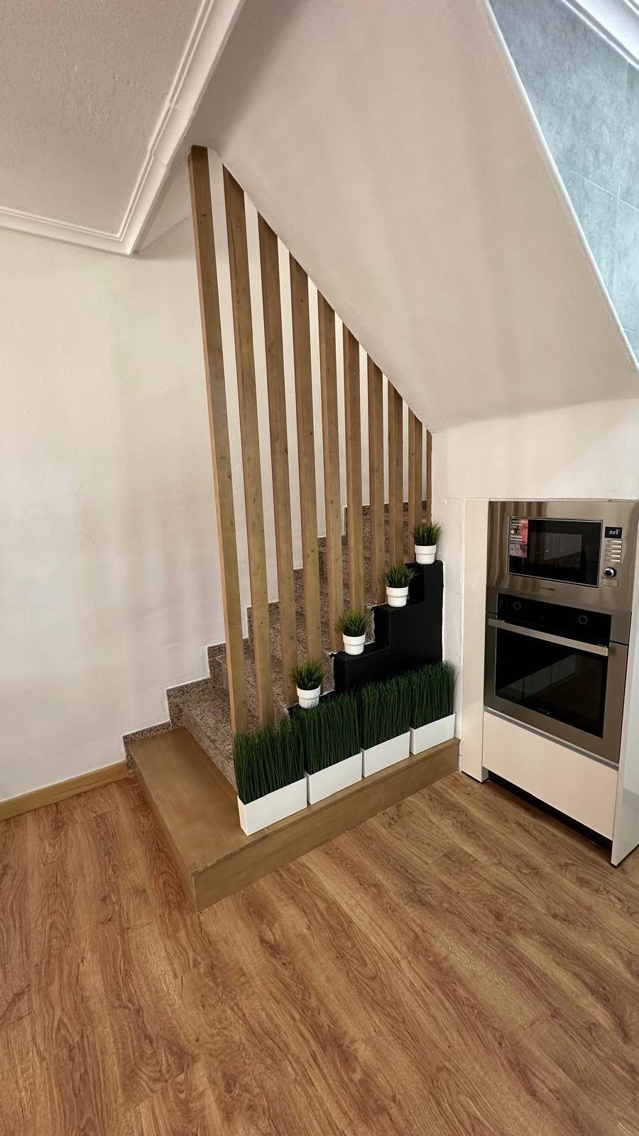 Moderne Küche mit integrierten Geräten und Treppenaufgang mit Holzlamellen.