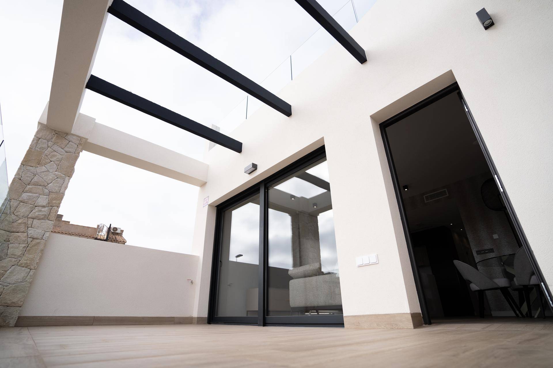 Moderner Balkon mit Holzboden und Zugang zum Innenbereich durch Glasschiebetüren.