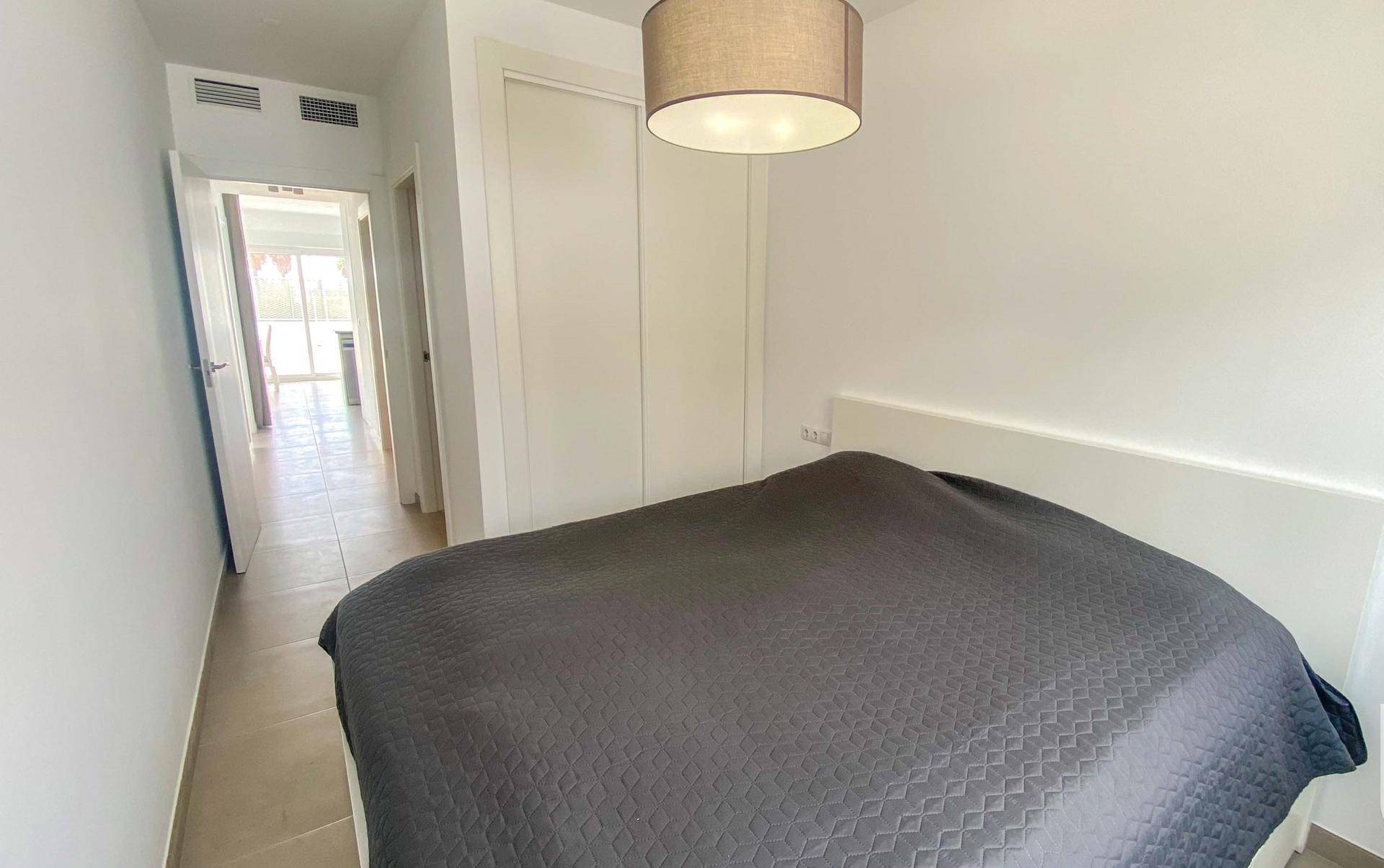 Schlafzimmer mit Doppelbett, Fliesenboden und Zugang zum Flur.