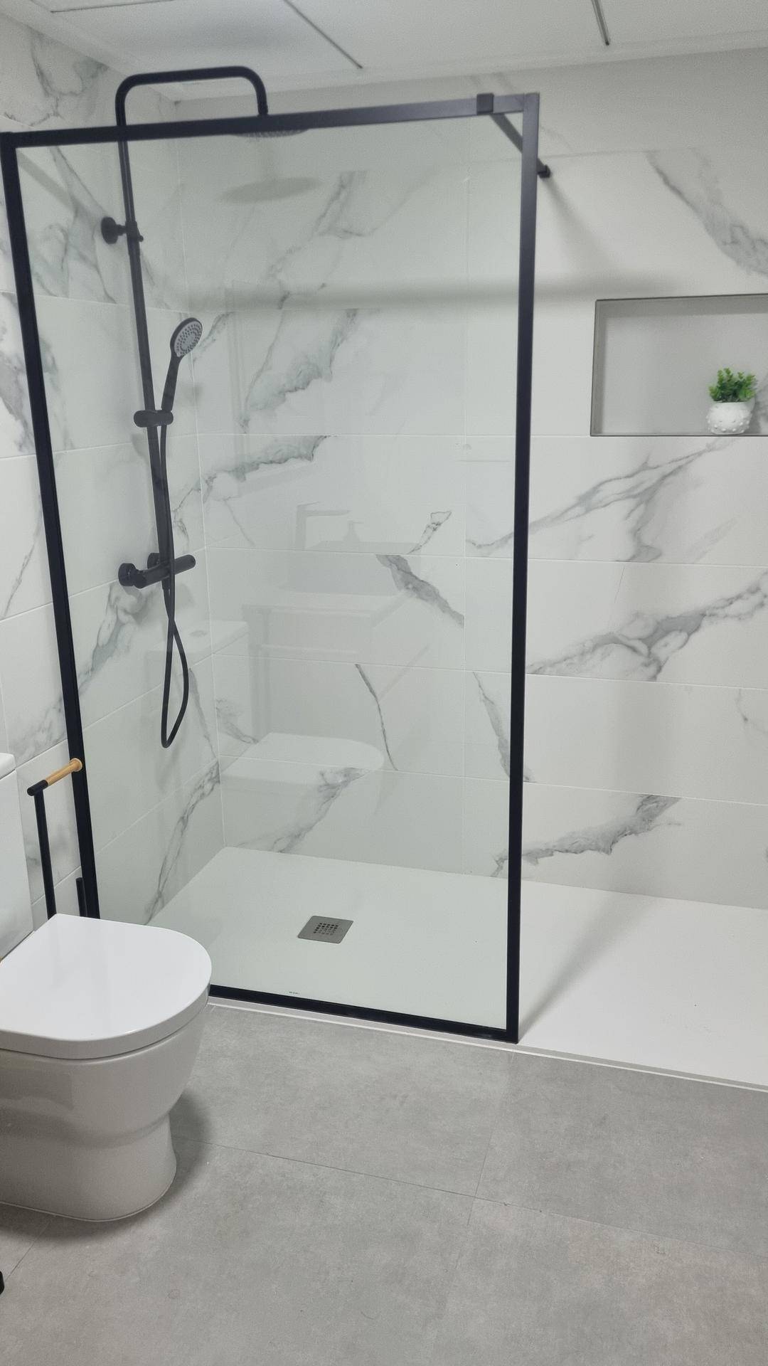 Modernes Badezimmer mit begehbarer Dusche, Marmorfliesen und minimalistischem Design.