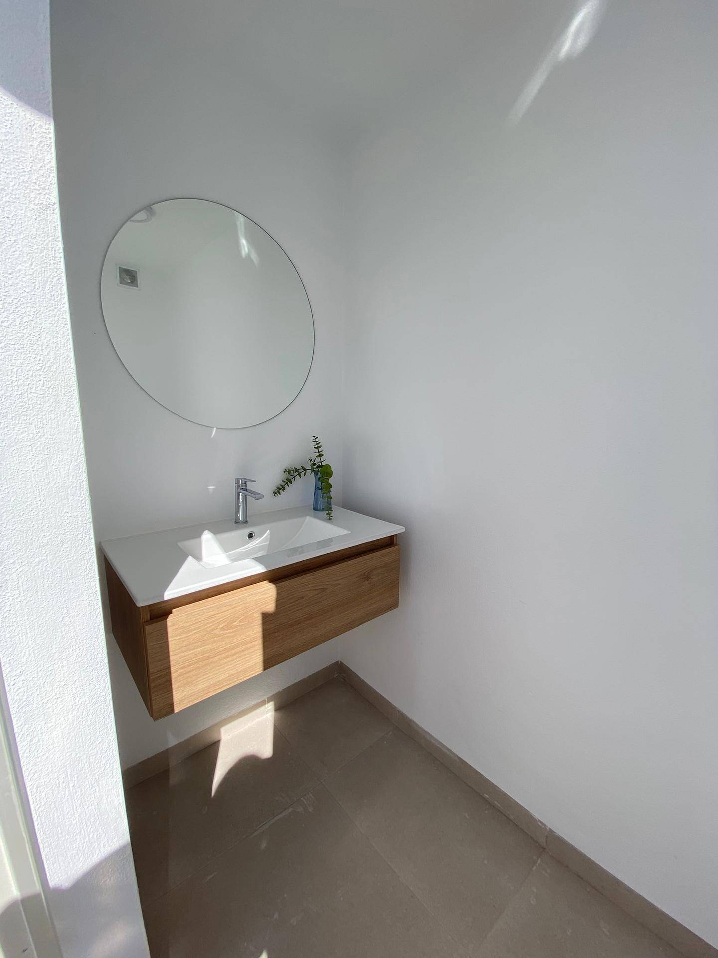 Modernes Gäste-WC mit schwebendem Waschtisch, rundem Spiegel und viel Tageslicht.