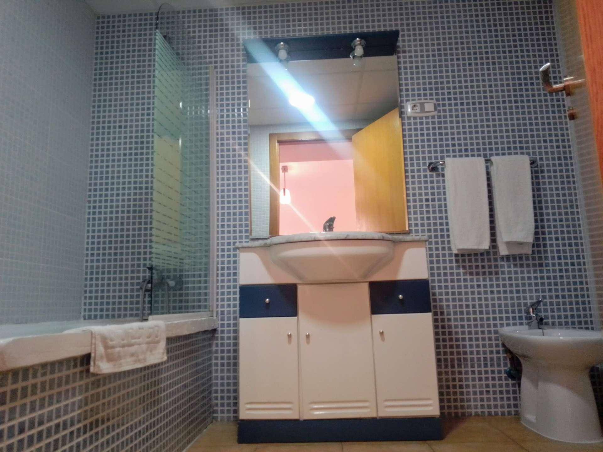 Badezimmer mit blauen Mosaikfliesen, Waschtisch, Badewanne und Bidet.