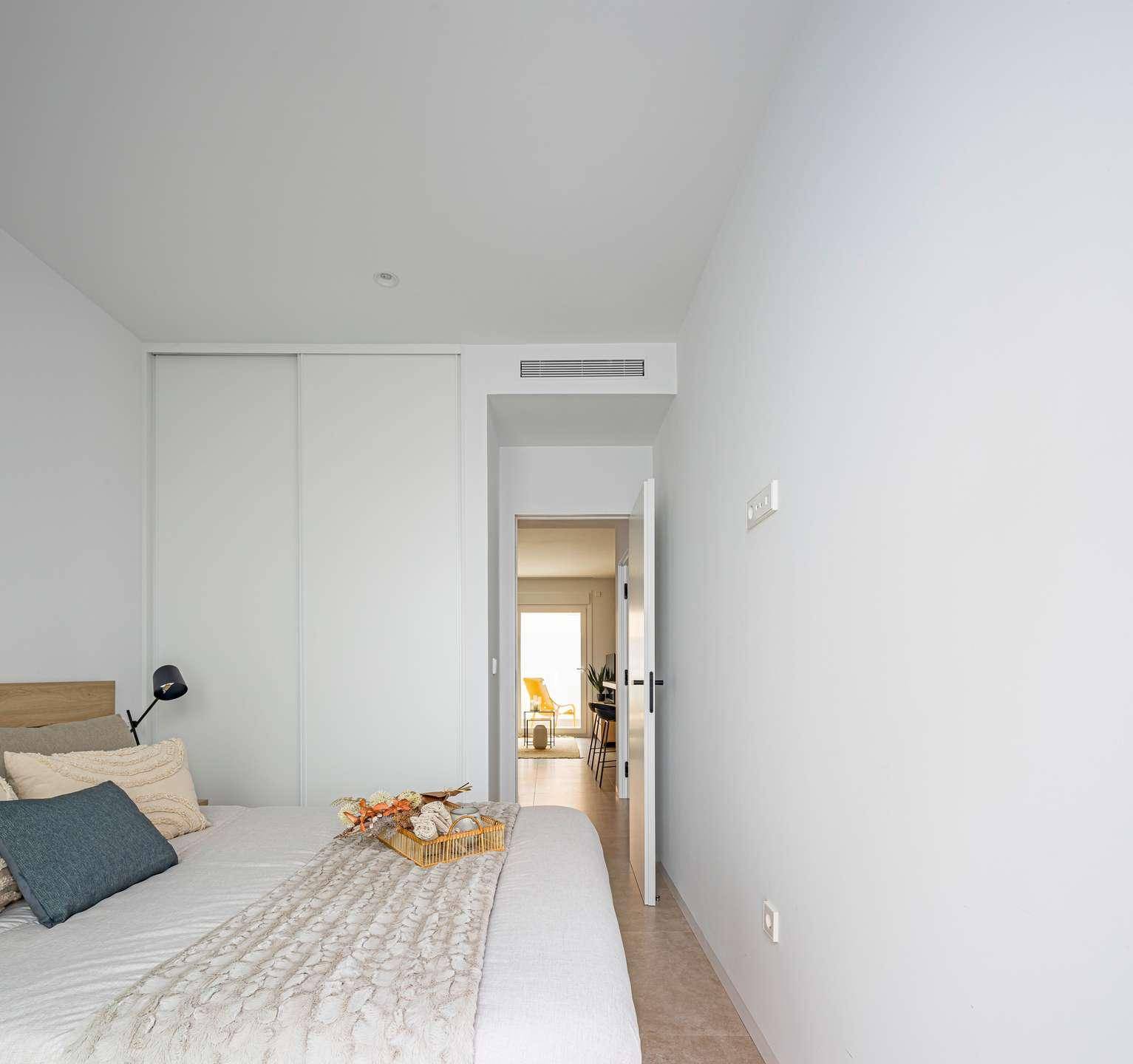 Helles Schlafzimmer mit integriertem Kleiderschrank und Zugang zu einem weiteren Wohnbereich.