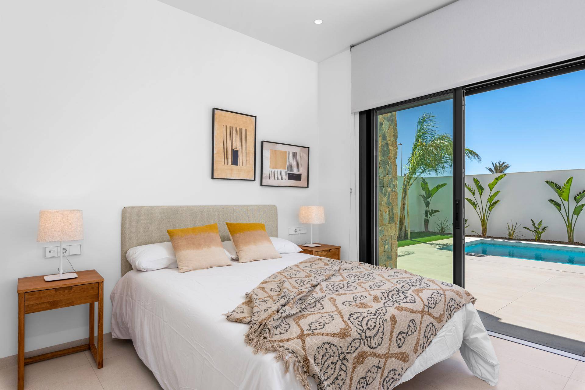 Schlafzimmer mit großem Fenster, Blick auf den Pool und direkten Zugang zum Außenbereich.