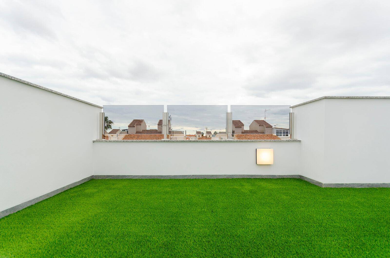 Dachterrasse mit Kunstrasen und Glasbrüstung bietet einen Blick auf die umliegenden Häuser.