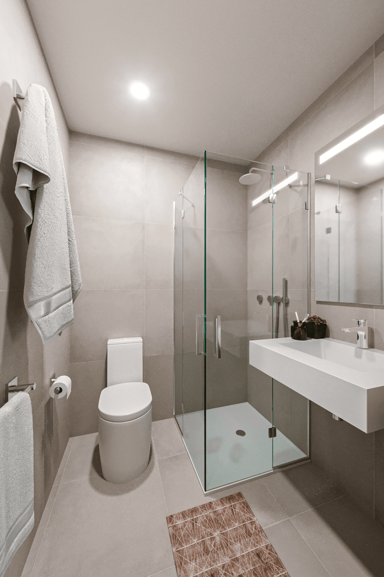 Modernes Badezimmer mit begehbarer Dusche, wandhängendem WC und elegantem Waschtisch in Grautönen.
