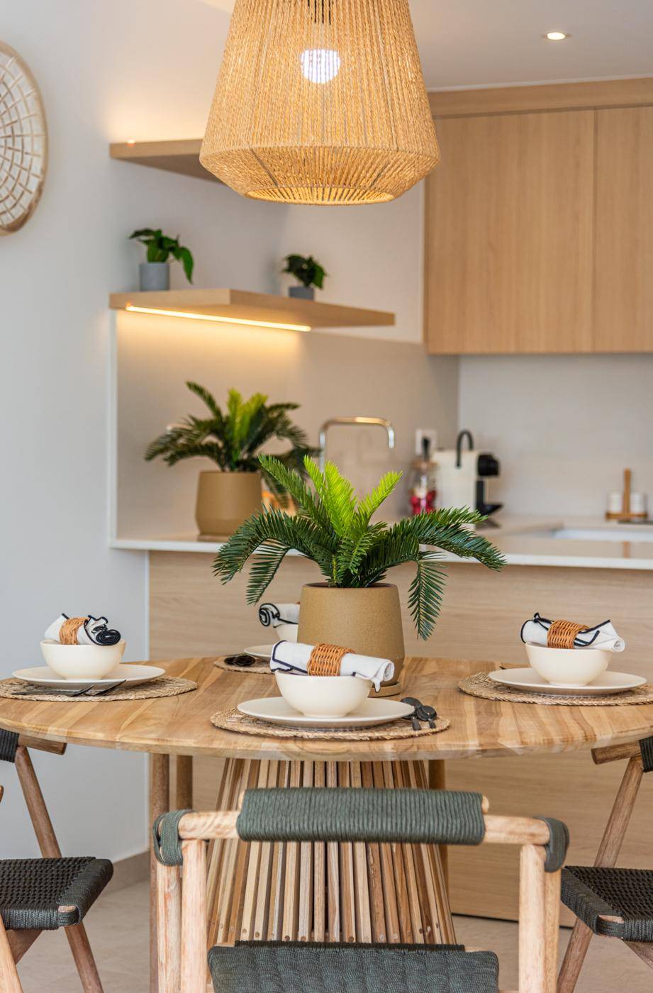 Gemütlicher Essbereich mit Rattan-Pendelleuchte und Blick auf die offene Küche.