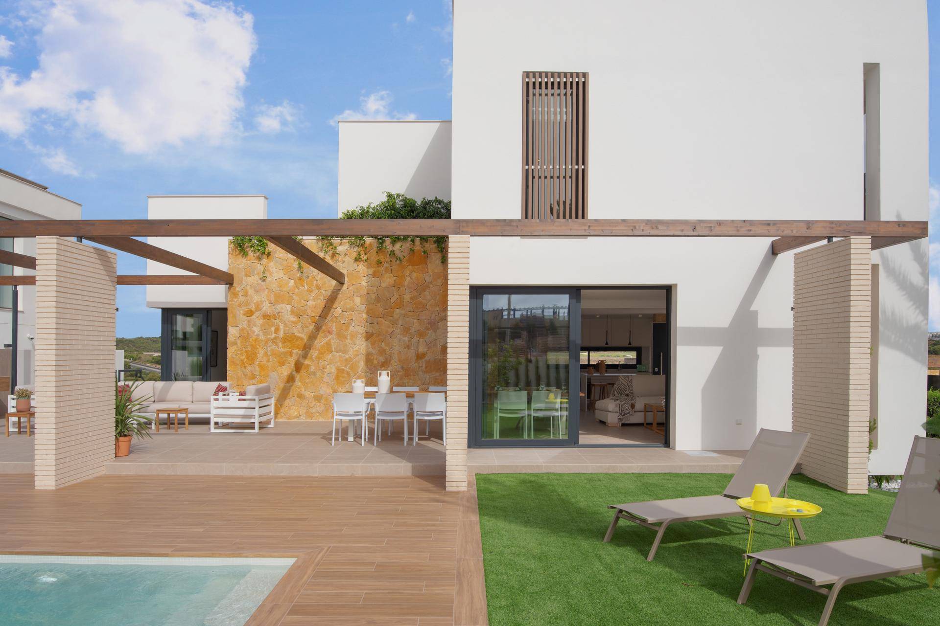 Blick vom Poolbereich auf die Villa mit Ess- und Lounge-Terrasse sowie Einblick in den Wohnbereich.
