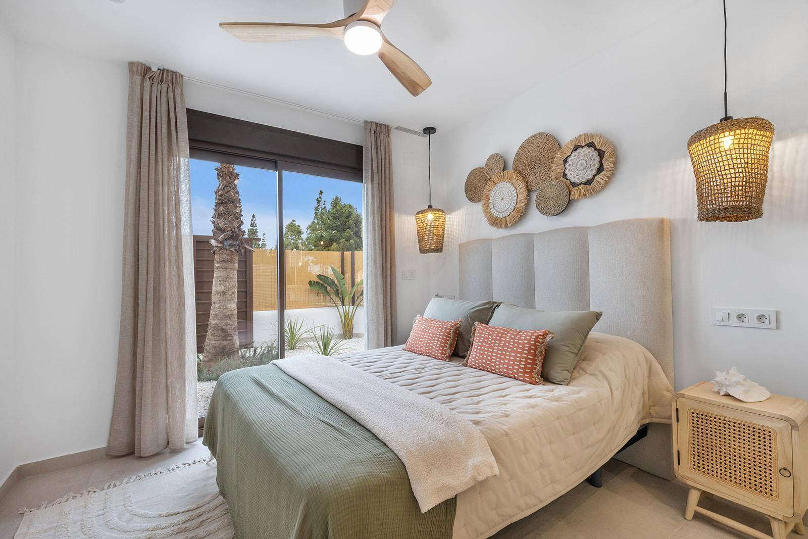 Schlafzimmer mit Deckenventilator, dekorativen Wandkörben und Zugang zum Außenbereich.