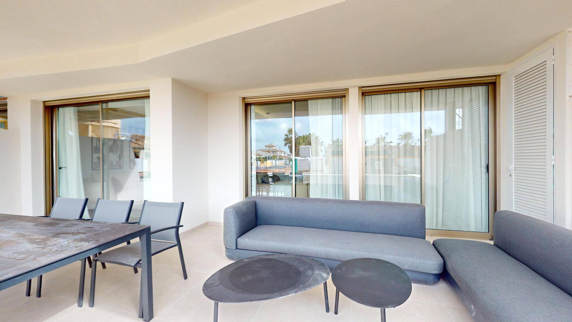 Geräumige überdachte Terrasse mit bequemen Loungemöbeln und Esstisch, ideal zum Entspannen.