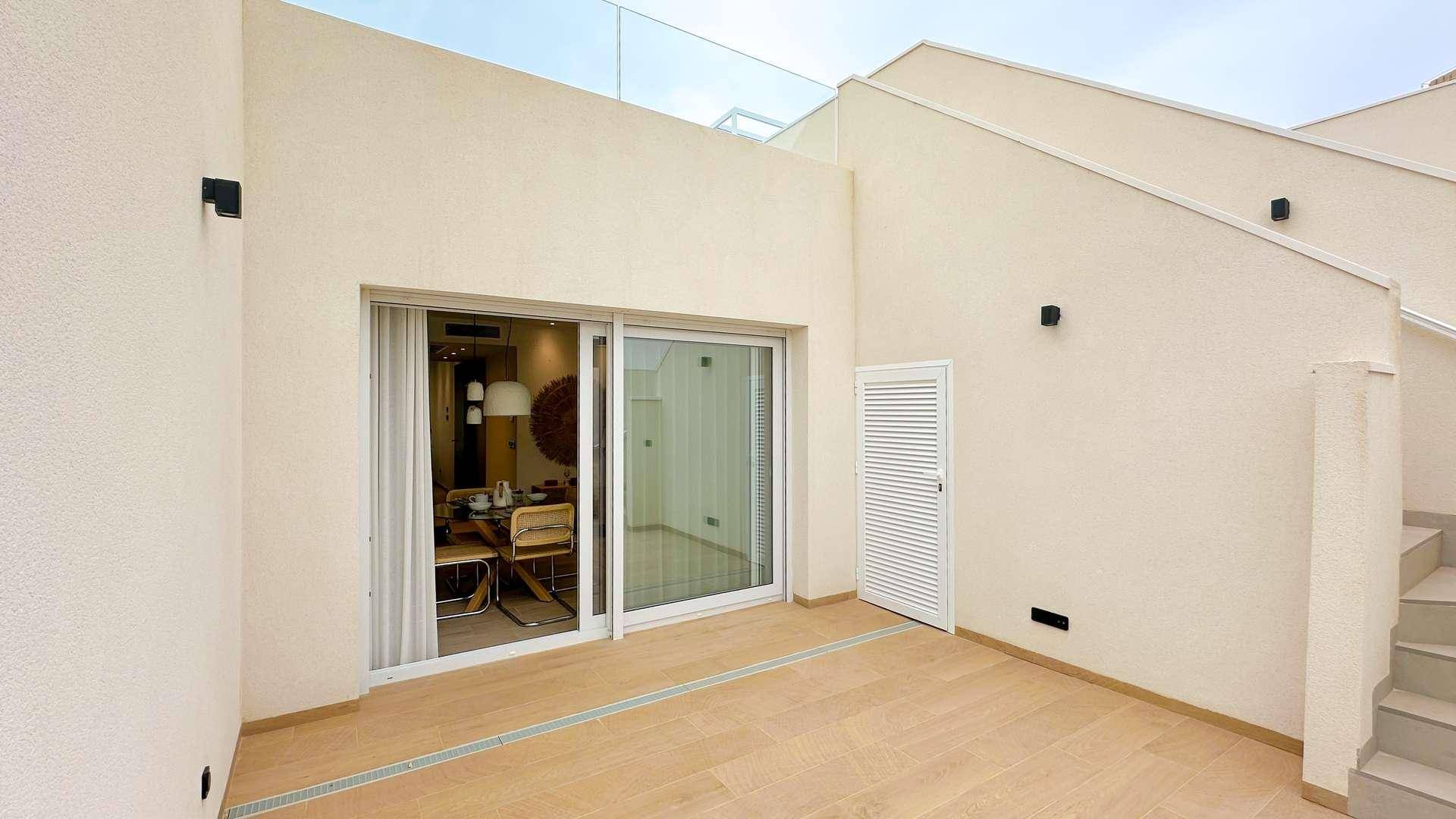 Geräumige Terrasse mit Zugang zum Innenbereich und Treppe zur oberen Ebene.