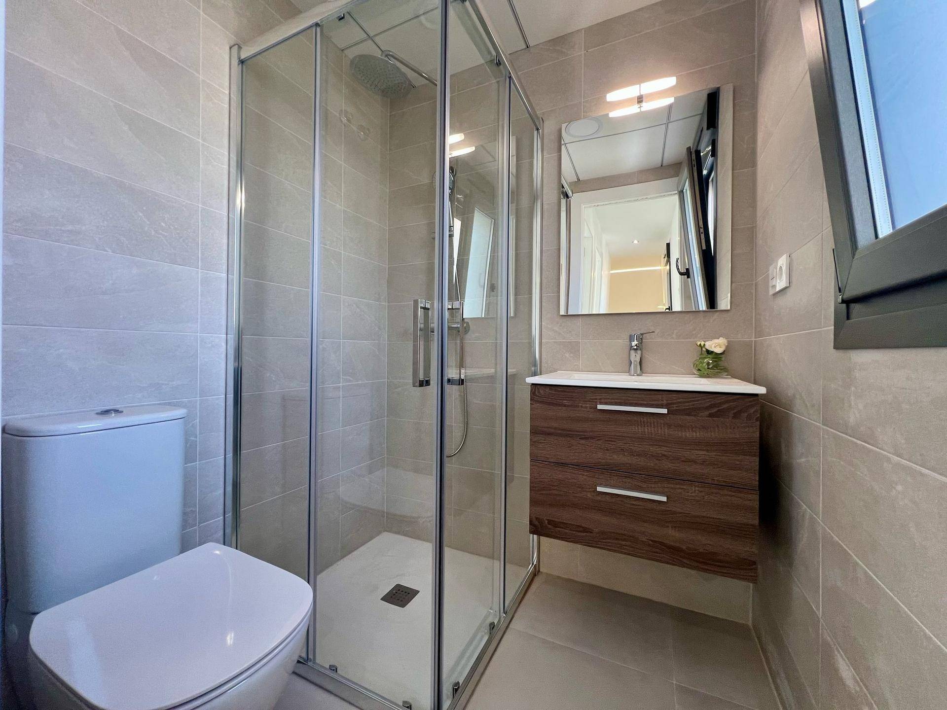 Modernes Badezimmer mit Duschkabine, wandhängendem WC und elegantem Waschtischunterschrank.