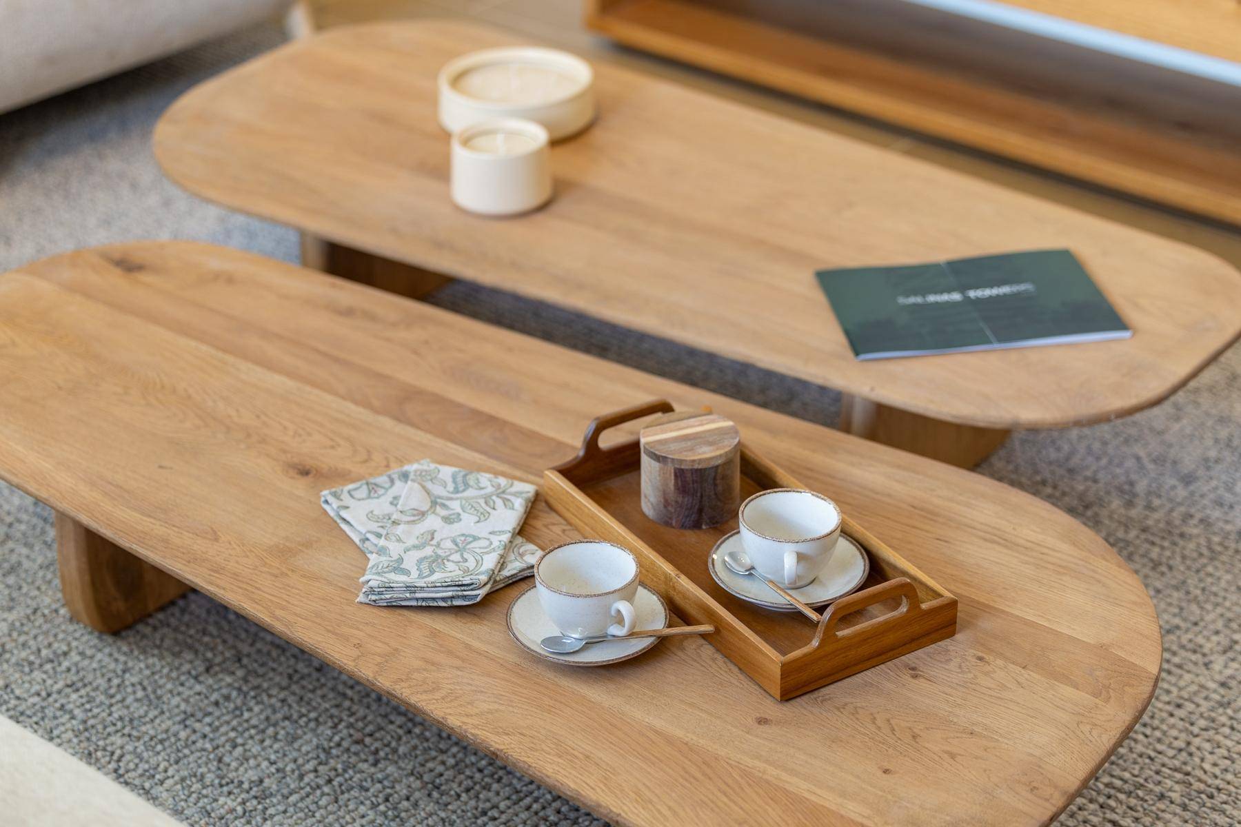 Detailaufnahme von zwei eleganten Holztischen mit einer Teetasse und dekorativen Elementen.