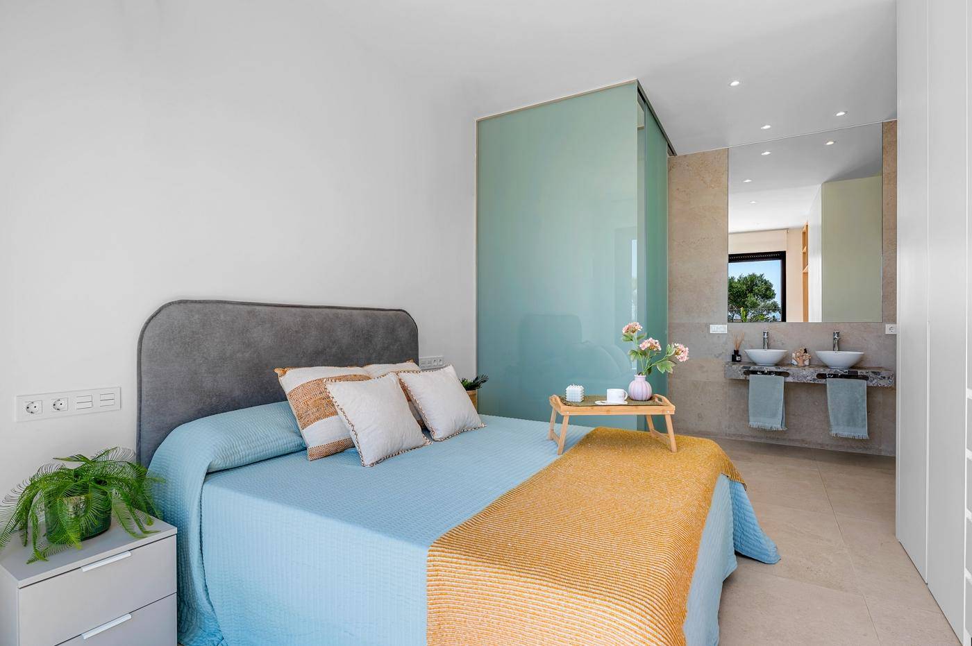 Modernes Schlafzimmer mit integriertem Badbereich, Doppelwaschbecken und stilvoller Einrichtung.